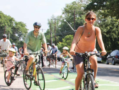 A group of cyclists, including younger children, move down a bike lane.